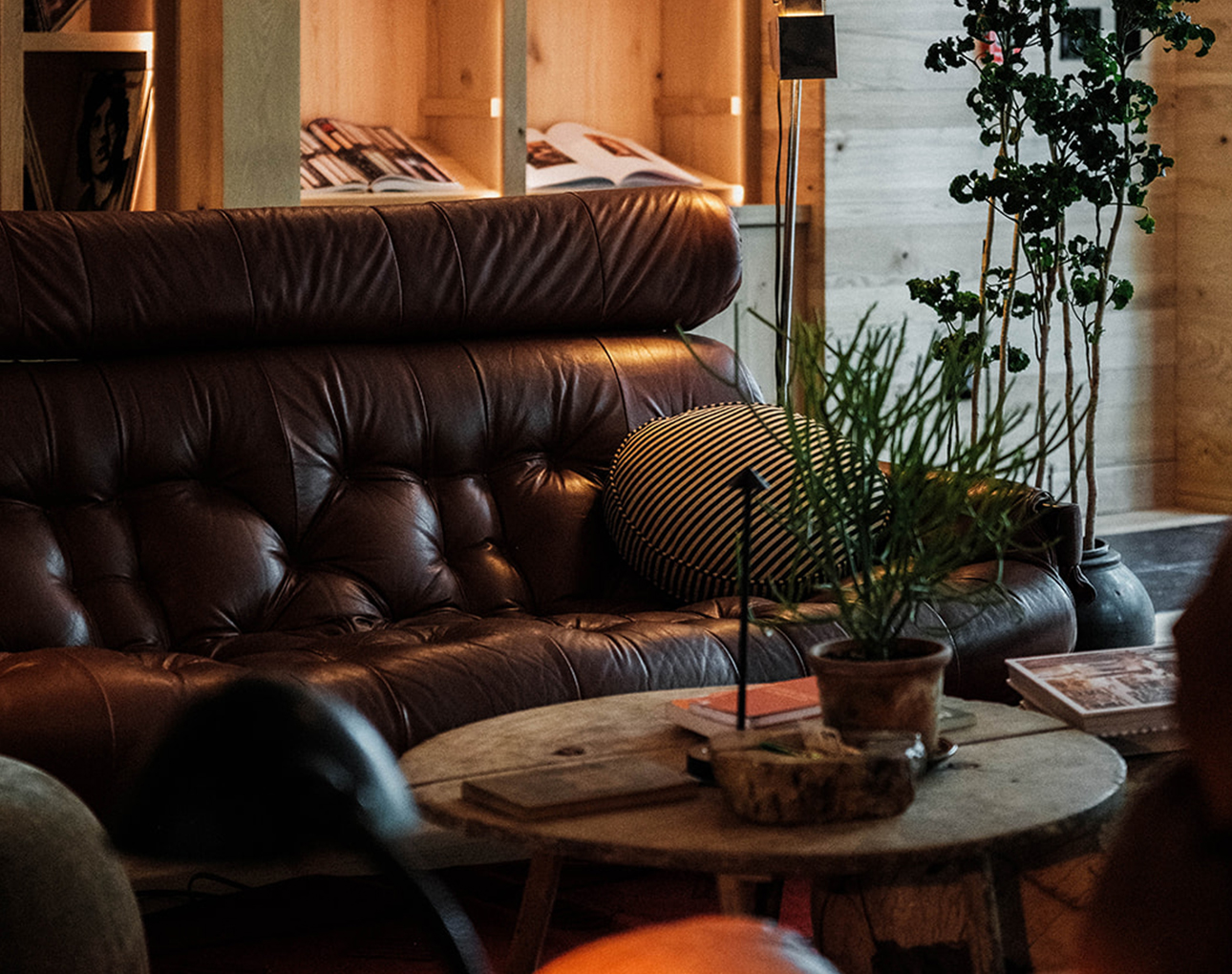 a brown leather couch with a striped pillow and a round coffee table