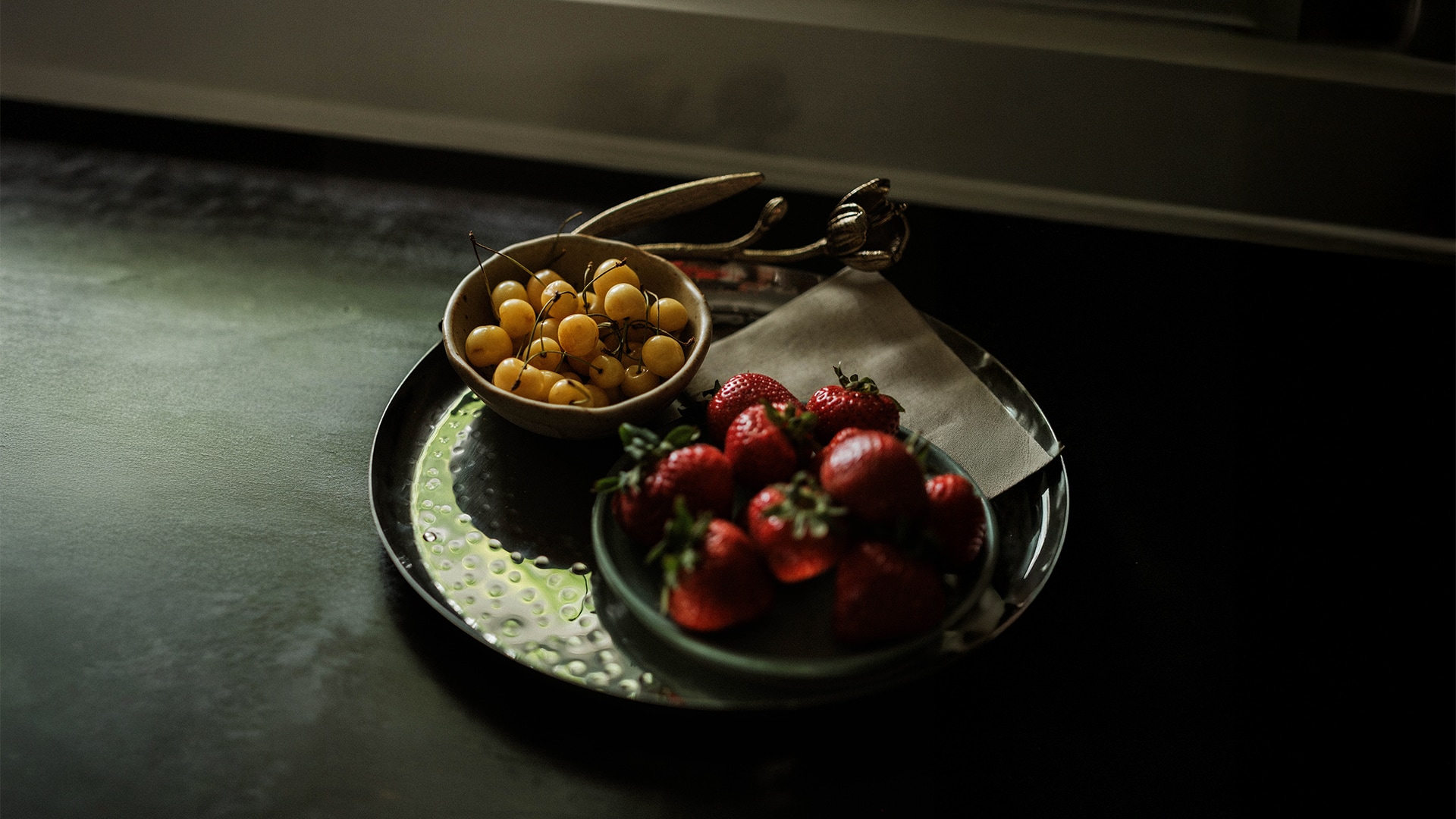a bowl of cherries and strawberries on a tray