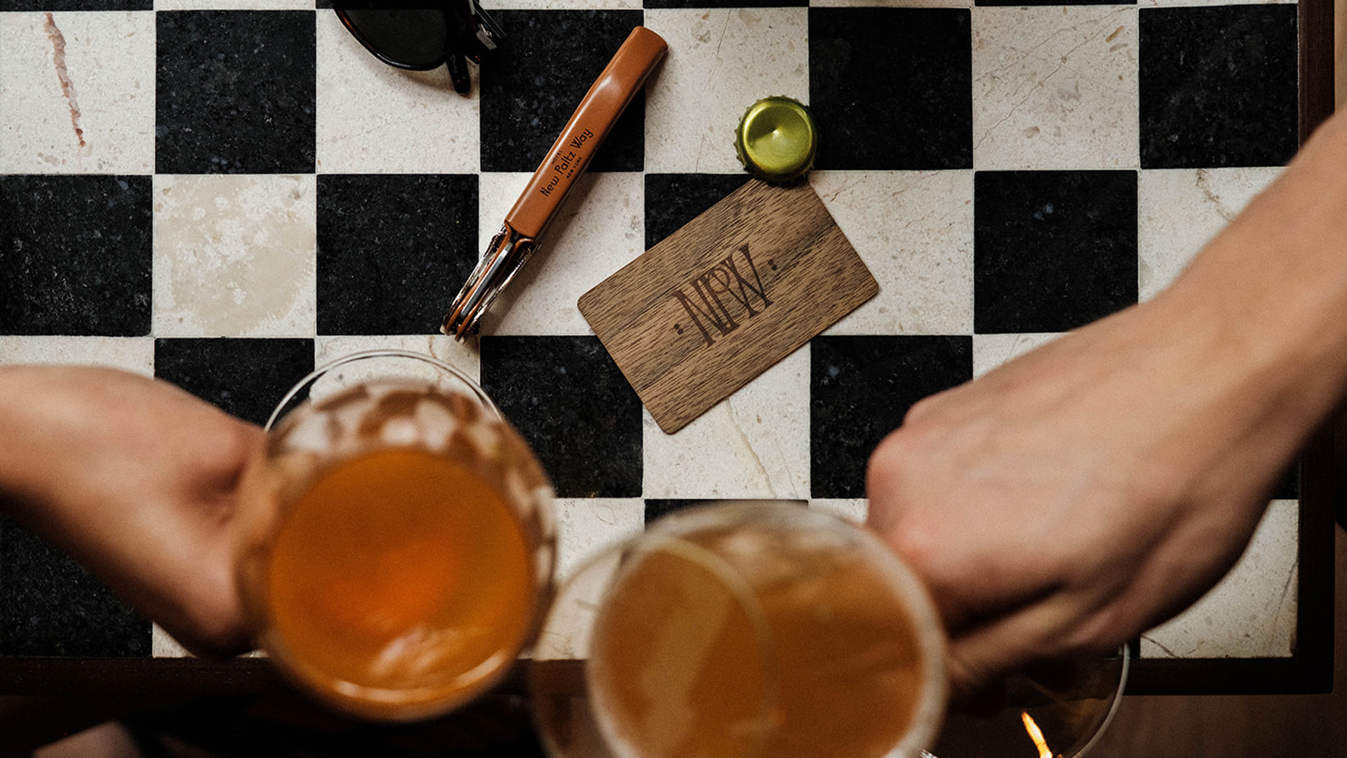 a pair of glasses of beer on a checkered surface