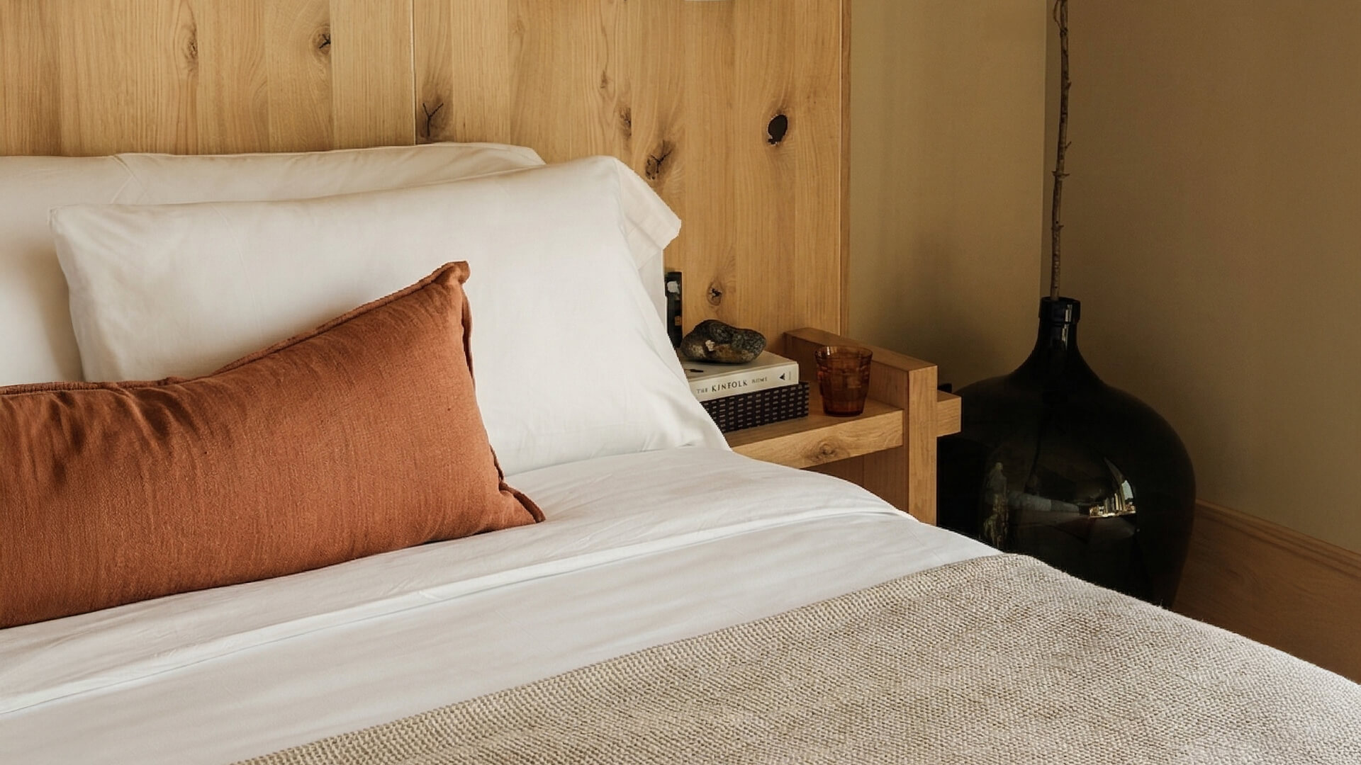 a bed with a pillow and a wood headboard