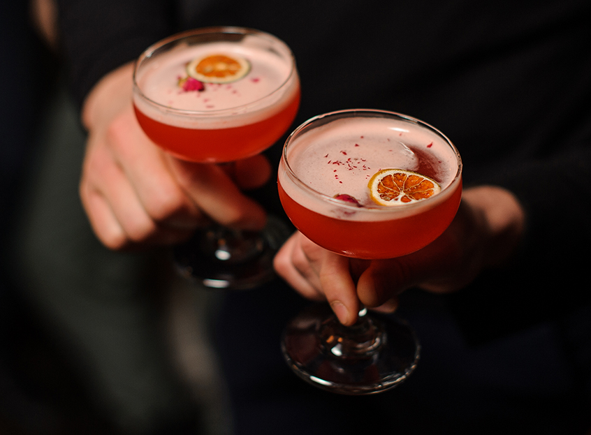 a pair of hands holding glasses with drinks