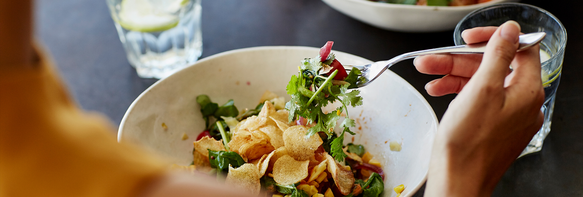 a fork holding a salad with chips and greens
