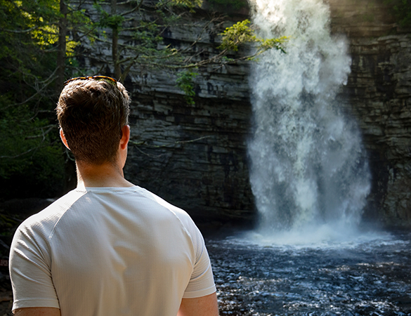 a man looking at a waterfall