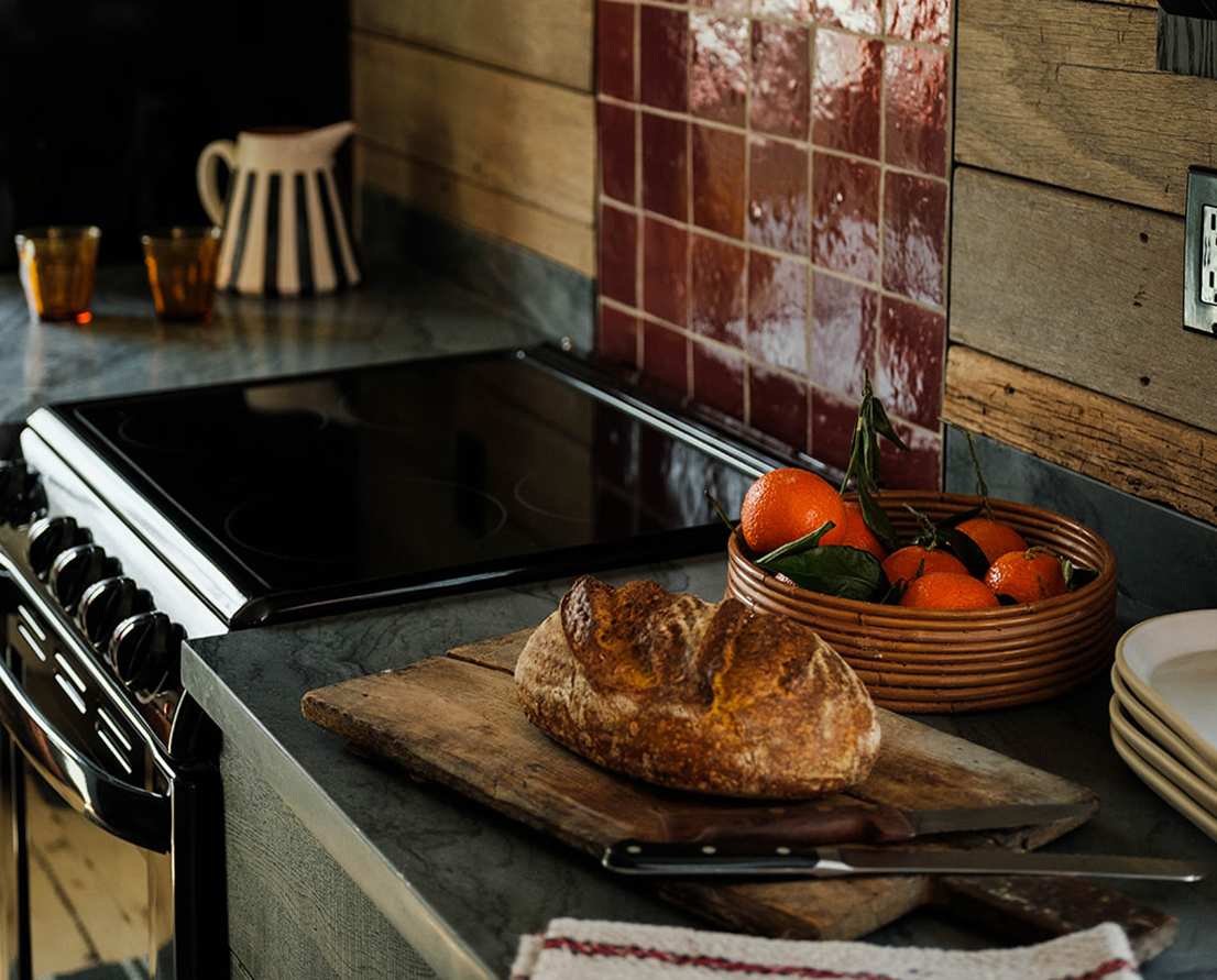 a bowl of oranges and a loaf of bread on a counter
