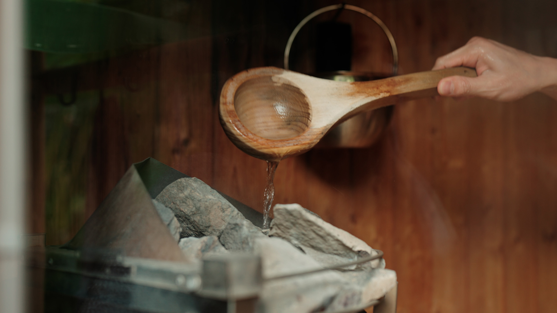 a wooden spoon pouring water into a bucket