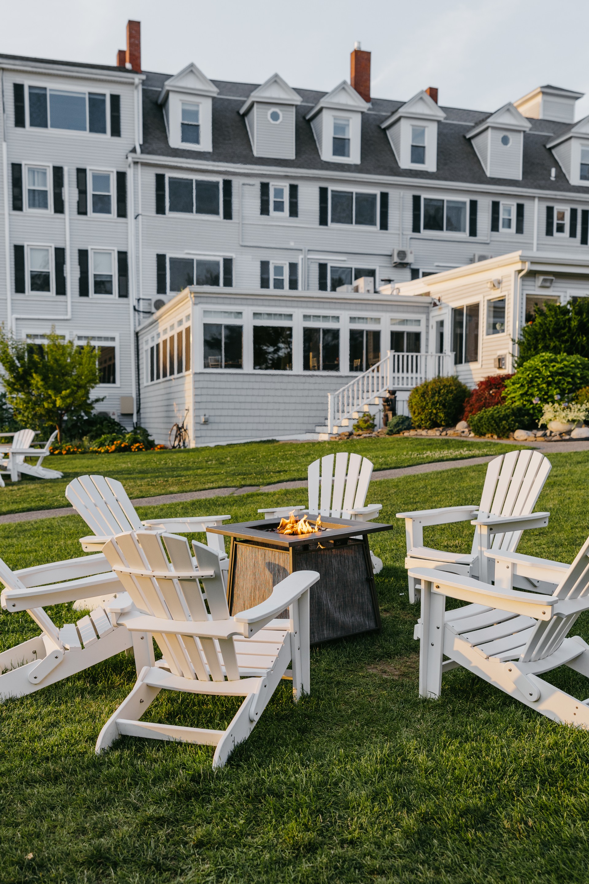 a lawn with chairs around a fire pit in front of a building