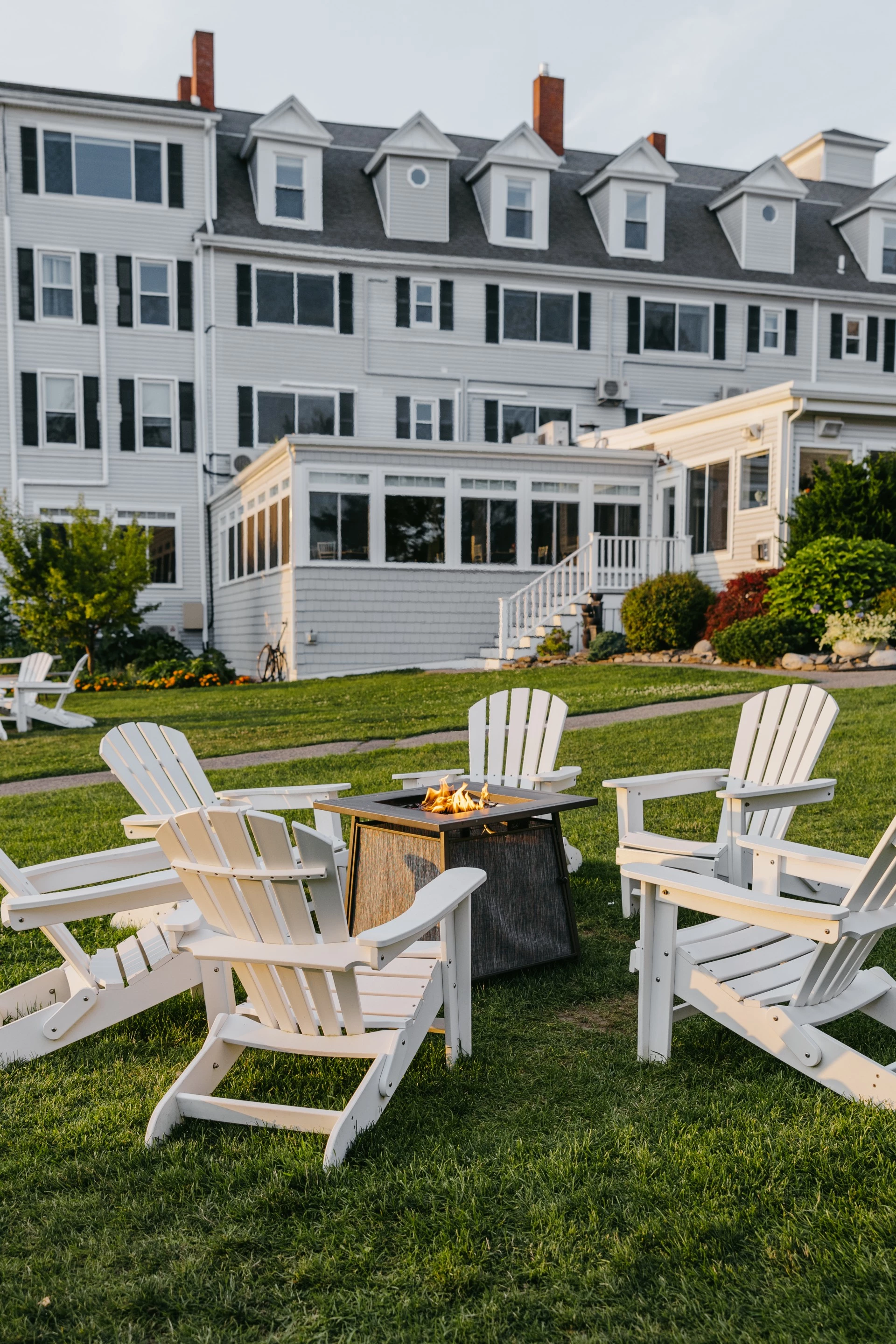 a lawn with chairs around a fire pit in front of a building