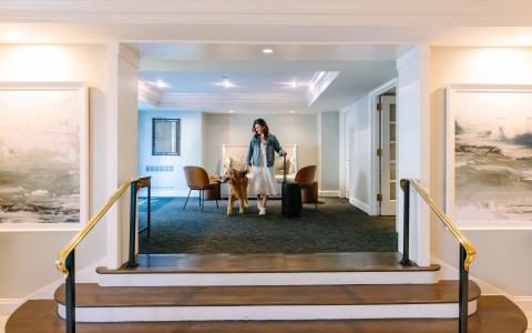 a woman walking a dog in a hotel lobby