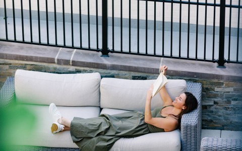 a woman lying on a couch reading a book