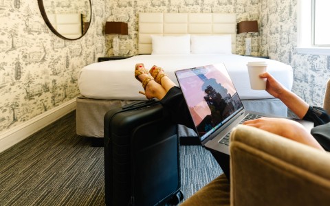 a person sitting in a chair with a laptop and a suitcase