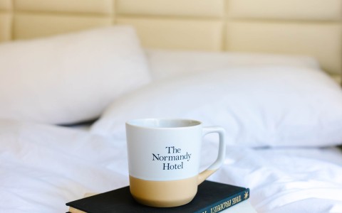 a coffee cup on a stack of books on a bed