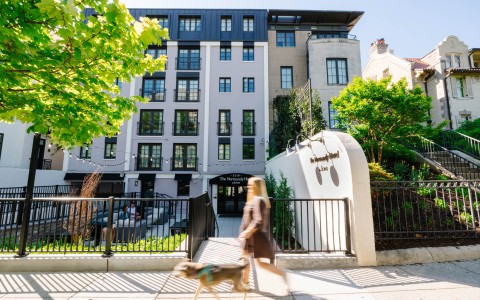a woman walking a dog in front of a building