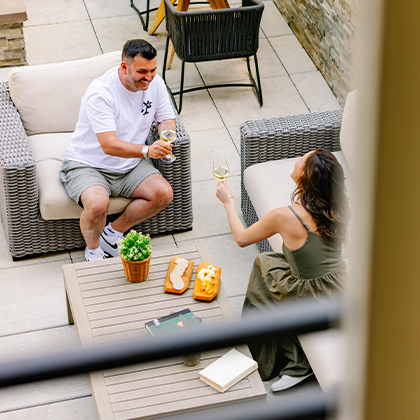 a man and woman sitting on a patio with a table and food