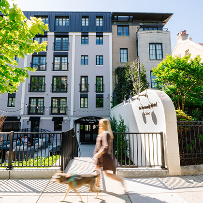a woman walking a dog in front of a building