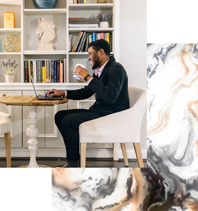 a man sitting at a table with a laptop and a cup of coffee