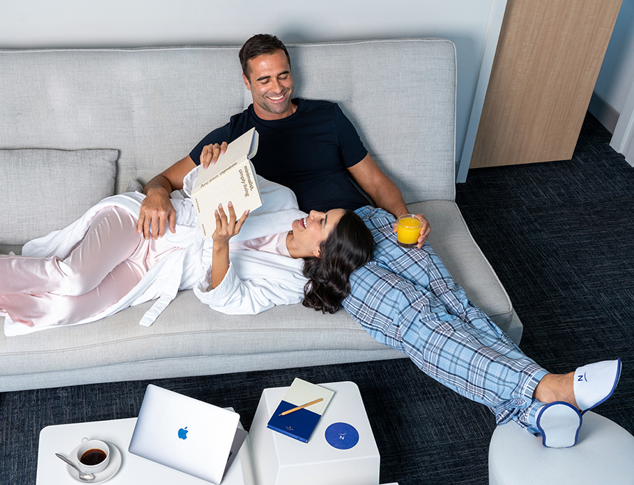 a man and woman lying on a couch reading a book
