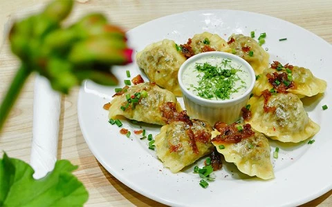 a plate of dumplings with a side dip