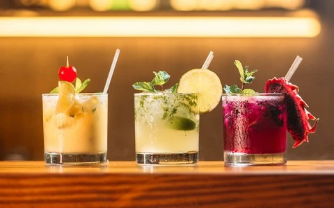 Three colorful cocktails on a bar