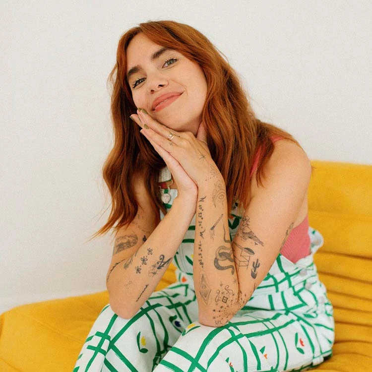 a woman with red hair and tattoos on her hands