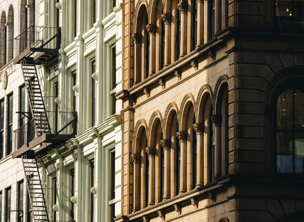 A close-up view of a building's exterior with a fire escape and arched windows.