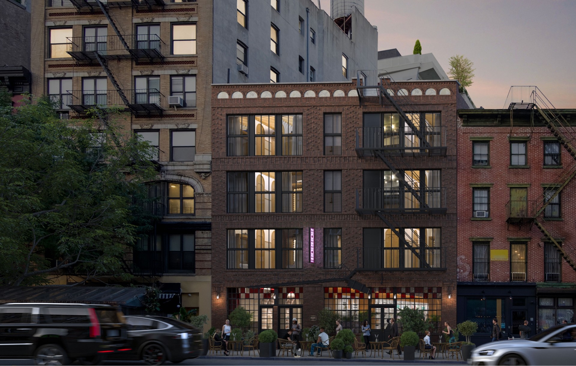 A three-story brick building with fire escapes and a street level seating area.