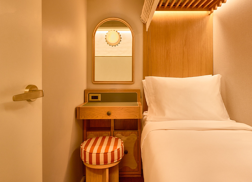 a bed with a stool and a mirror