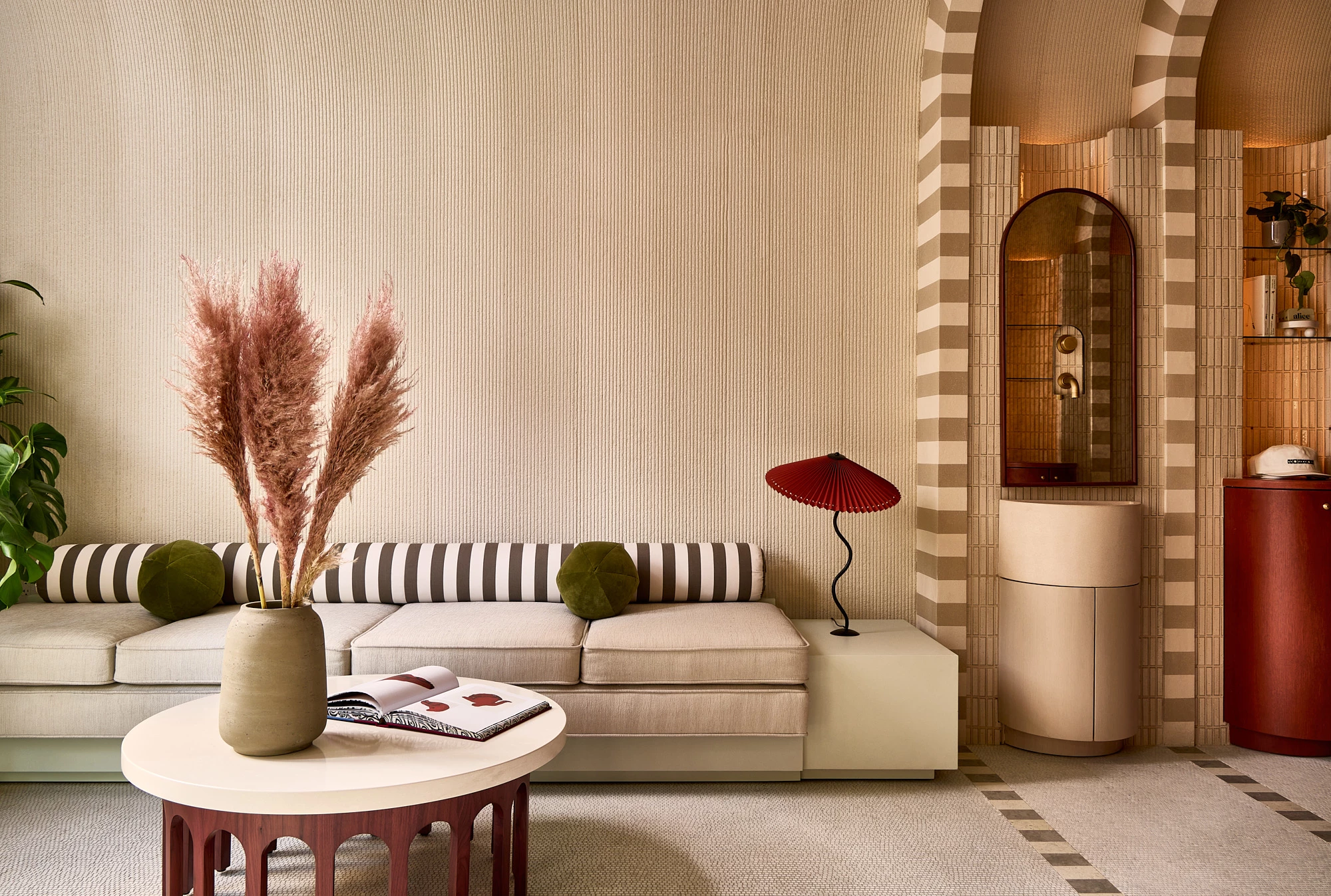 A stylish lobby lounge with a curved sofa, coffee table, and decorative items.