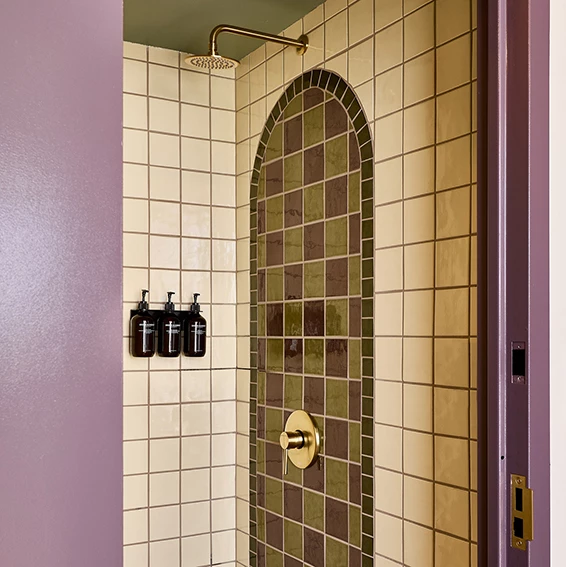 A shower with tiled walls and toiletries