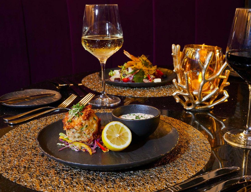 black dinner plates filled with delicious food, paired with white and red wine