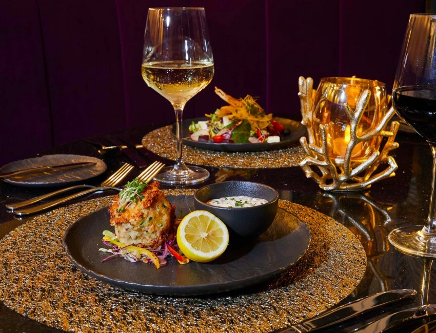 black dinner plates filled with delicious food, paired with white and red wine