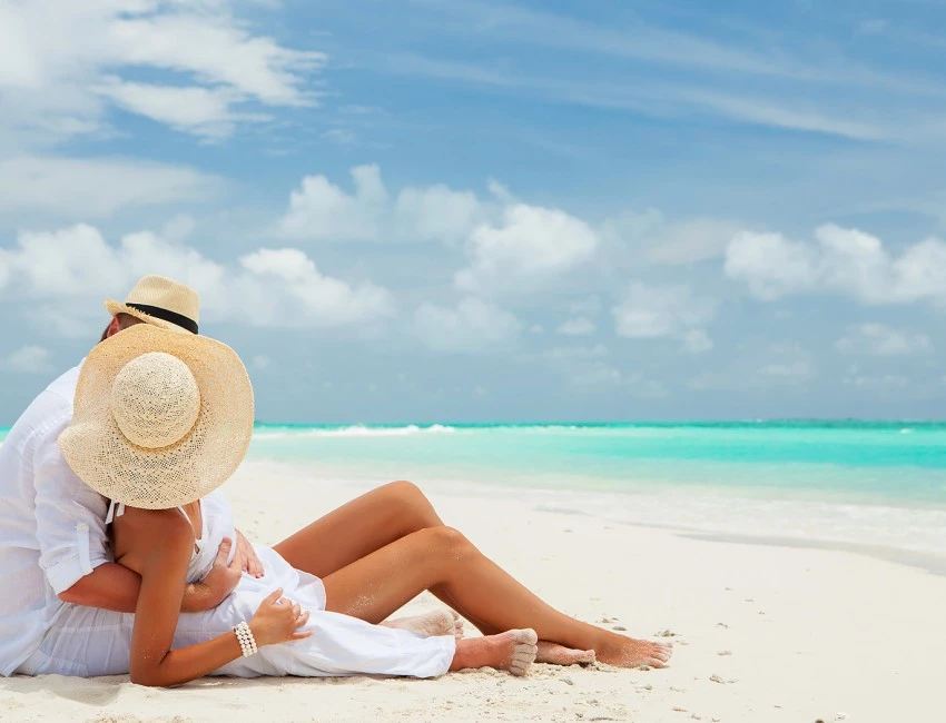 man and woman laying on the beach