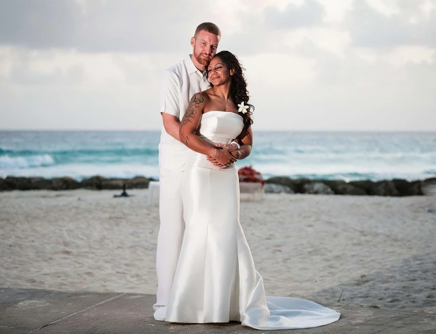 bride and groom posing in front of the beach
