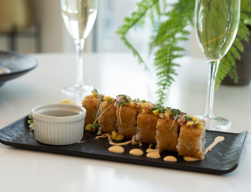 a plate of sushi with sauce and a plant