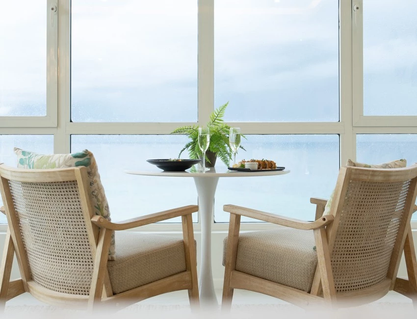 a table with food on it and chairs in front of a window