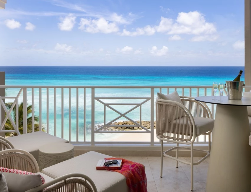 a balcony with chairs and a table and a view of the ocean