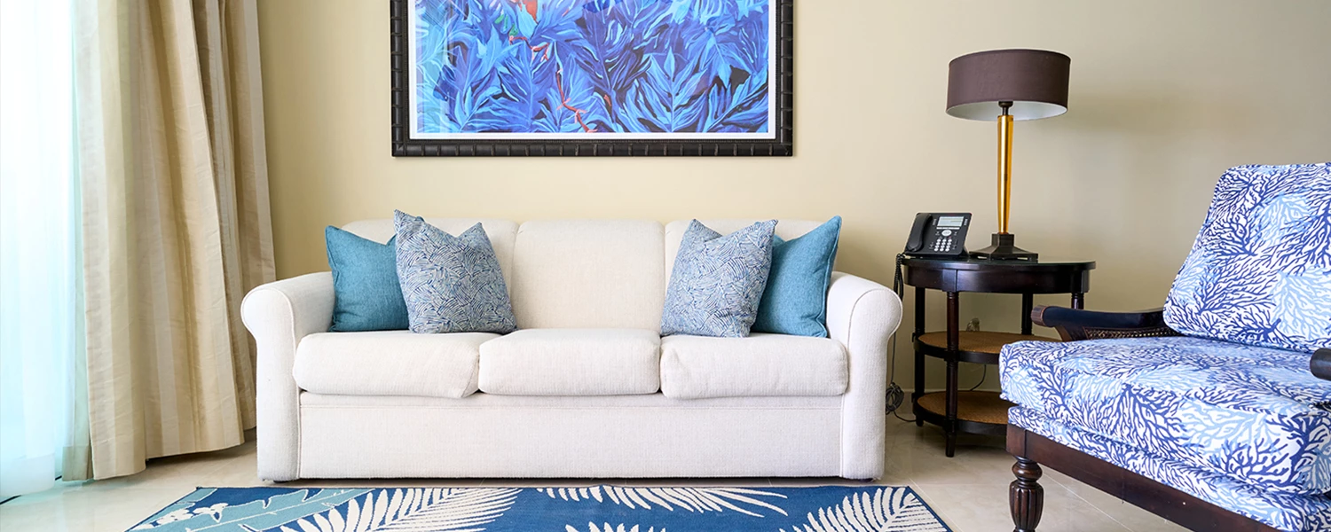 white couch with chair next to it and blue feather painting above it