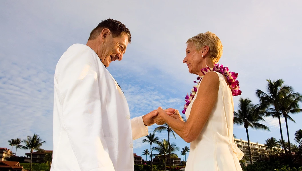 older couple smiling holding hands facing each other