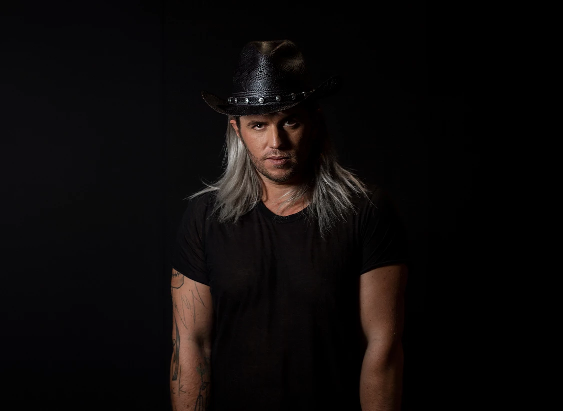 a man with long hair wearing a cowboy hat
