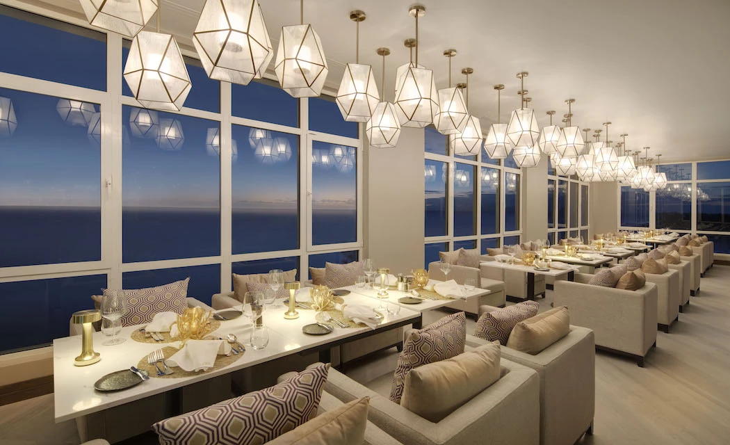 long tables with cushioned chairs and chandeliers hanging above
