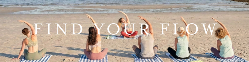 a group of people doing yoga on the beach