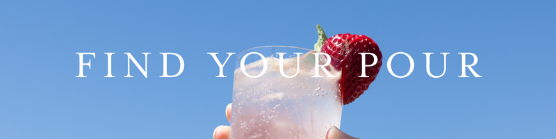 a hand holding a glass of liquid with a strawberry on top