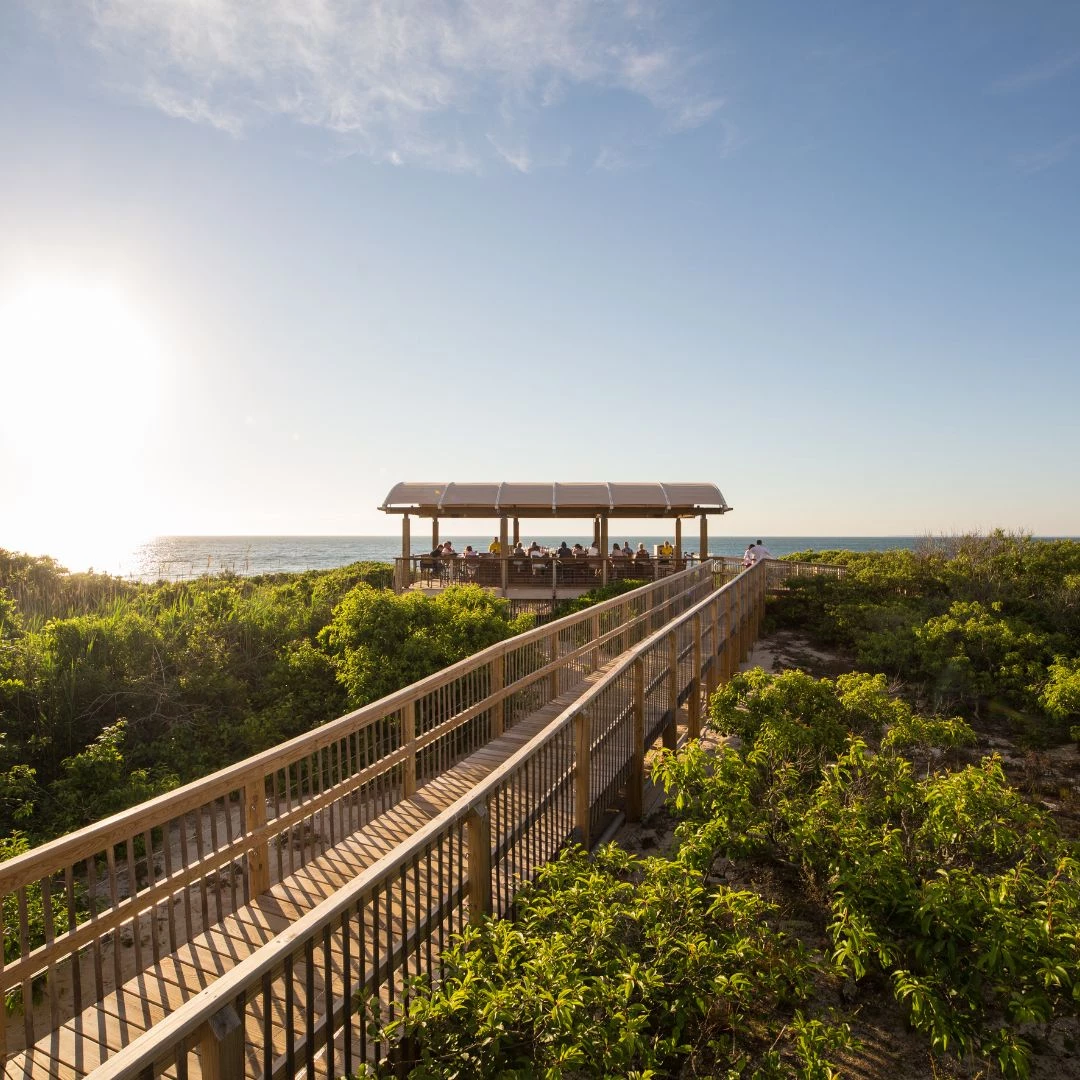 a boardwalk with a gazebo and bushes