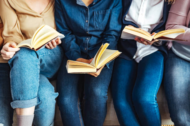 a group of people sitting on a couch reading books