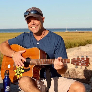 a man sitting on a rock playing a guitar