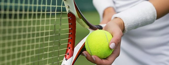 woman holding a tennis ball in front of her racket about to serve
