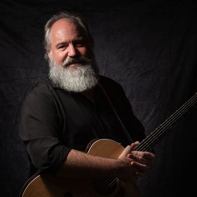 a man with a beard holding a guitar