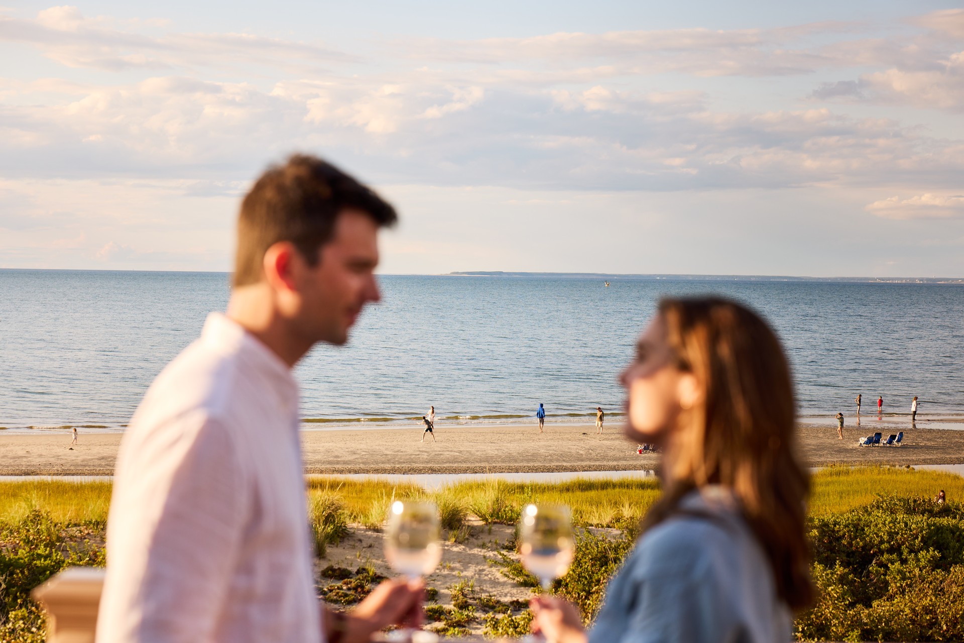 a man and woman holding wine glasses on a beach