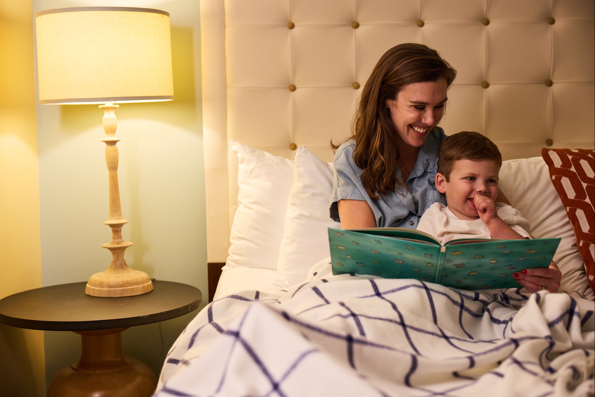 a woman and a baby reading a book in bed