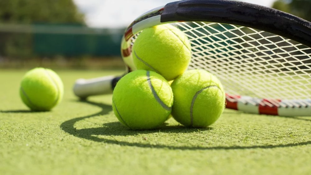 a group of tennis balls and a racket on a court