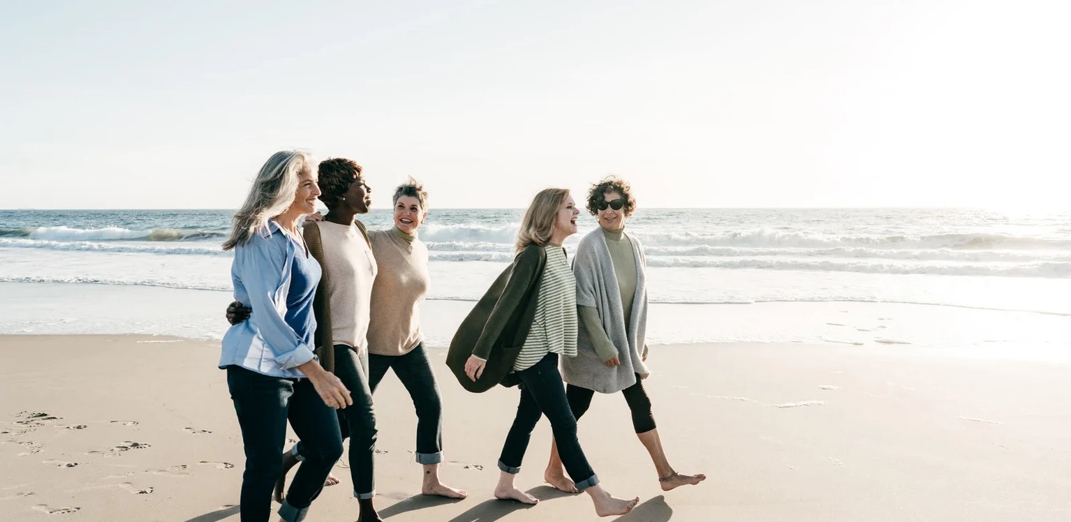 a group of women walking on a beach
